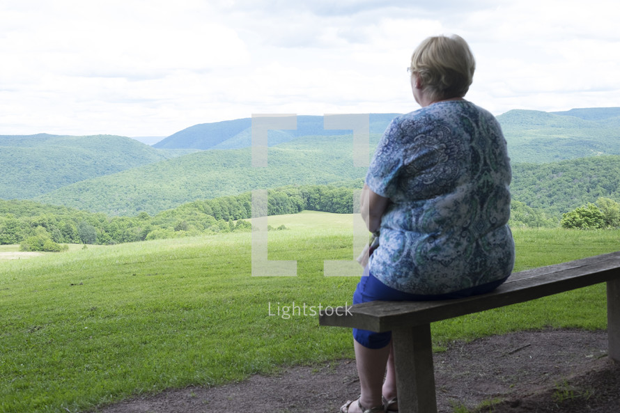 a woman looking out at a green landscape 
