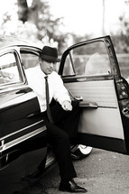 man in a suit and hat getting out of an old car vintage 1950's men