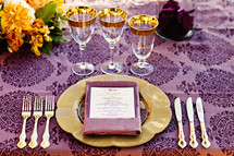 Formal dinner setting at table purple gold orange