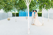 A bride and groom kissing sculpture art orchard trees blue wall wedding love dress
