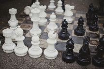 White and black chess pieces sit atop a highly used chess board.