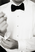 man putting on a tuxedo shirt buttoning sleeve Bow tie 