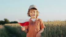 Polish little boy standing with national flag. 