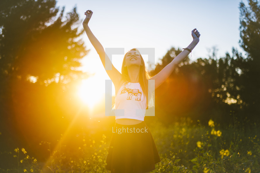 teen girl with raised arms standing outdoors 