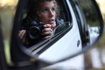 woman sitting in her car holding a camera 