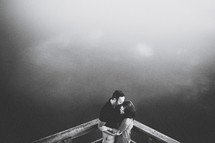 a couple kissing on a dock over water 