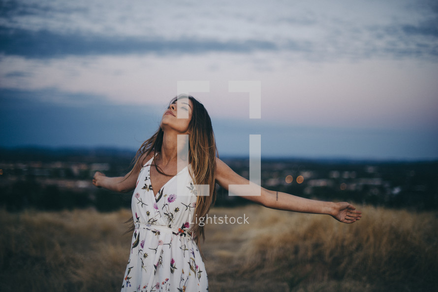 a woman with outstretched arms standing outdoors 