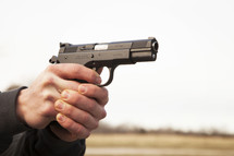 A man's hands holding and aiming a handgun.