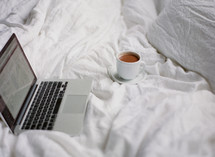 laptop and mug on a bed 
