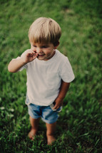 a toddler boy standing barefoot in the grass 