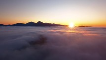 Aerial view of golden sunset above clouds in evening mountains nature landscape
