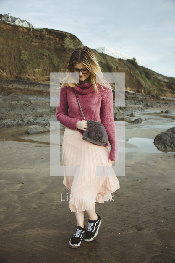 a woman in a skirt walking on a beach 