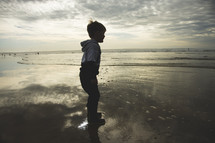 toddler boy playing in puddles on a beach