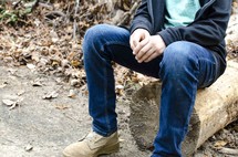 legs of a boy sitting on a log 