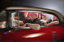 Men laughing inside a vintage red car