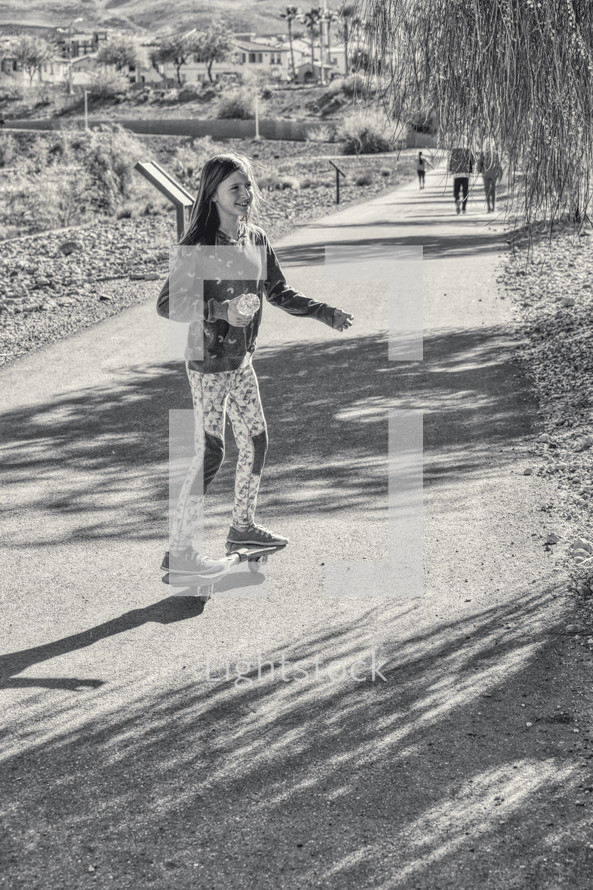a child riding a skateboard on a path at a park 