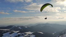 Freedom adventure of paragliding flying above winter alpine mountains, free flight extreme sport
