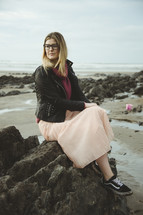 a woman sitting on a rock on a beach 