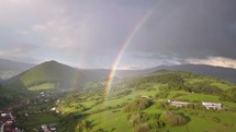 Aerial view of double rainbow above green country landscape in summer evening with rain and sun light
