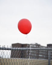 red balloon tied to a fence 