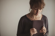 Woman praying as she holds her Bible