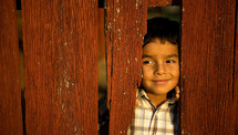 Boy peeking through wood fence