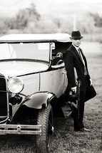 gangster man in front of an old car holding a tommy gun