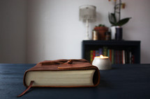 leather bound Bible and candle on a blue desk 