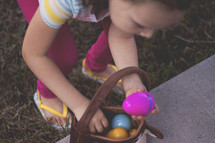 girl putting Easter eggs in an Easter basket 