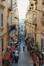 Alleyway with motorbike driving among old houses in Naples, Italy