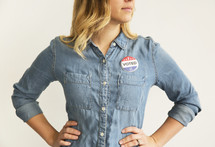 A young woman in a denim shirt with a button reading, "I Voted."