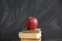 an apple on a stack of books and blackboard 