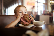 Little child having lunch with sandwich 