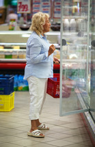 Woman choosing products in open fridge