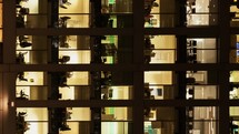 Vertical night to day timelapse of the exterior of an office block at night revealing the daily activity of office workers night themes of routines working late deadlines