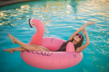 a woman relaxing in a flamingo pool float 