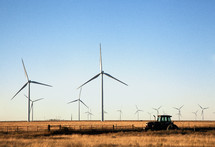 wind turbines and a tractor in a field 