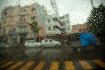 view of parked cars and a crosswalk through a wet window 