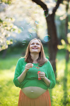 Happy pregnant woman and bubbles outdoor