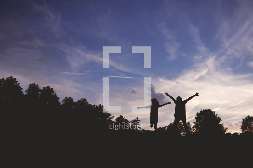 silhouettes of children jumping outdoors 
