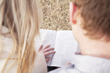 young couple reading a Bible together outdoors 