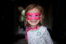 a girl child in a cape and mask 