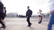 Time-lapse of commuters walking at rush hour backlit against the sun on London Bridge.