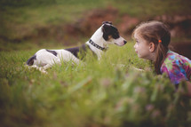 a child and her dog in the grass 