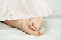 infant bare feet peeking out of a baptismal gown 