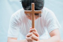 a man holding a wooden cross praying 