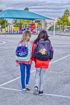 two students with book bags walking home after school 