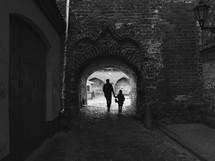 father and son walking holding hands on a cobblestone street 