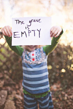 girl holding a sign that says "The grave is empty"