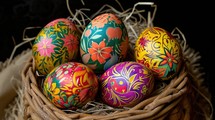 Painted easter eggs in a wicker basket on a black background